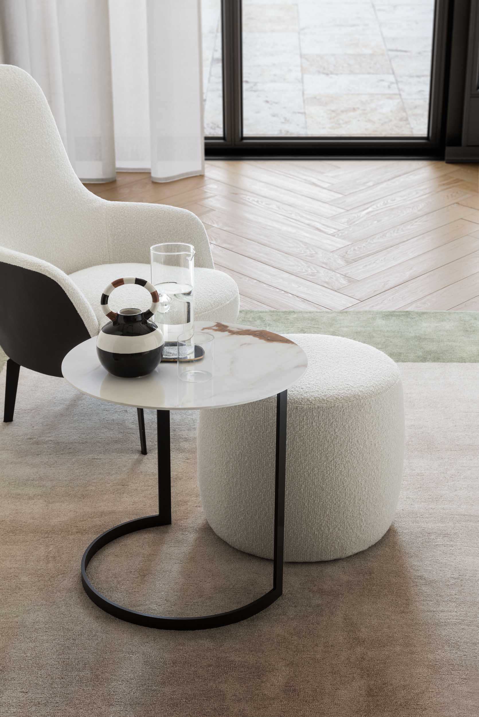 Coffee table with light Calacatta gres top and pouf nested in its structure.