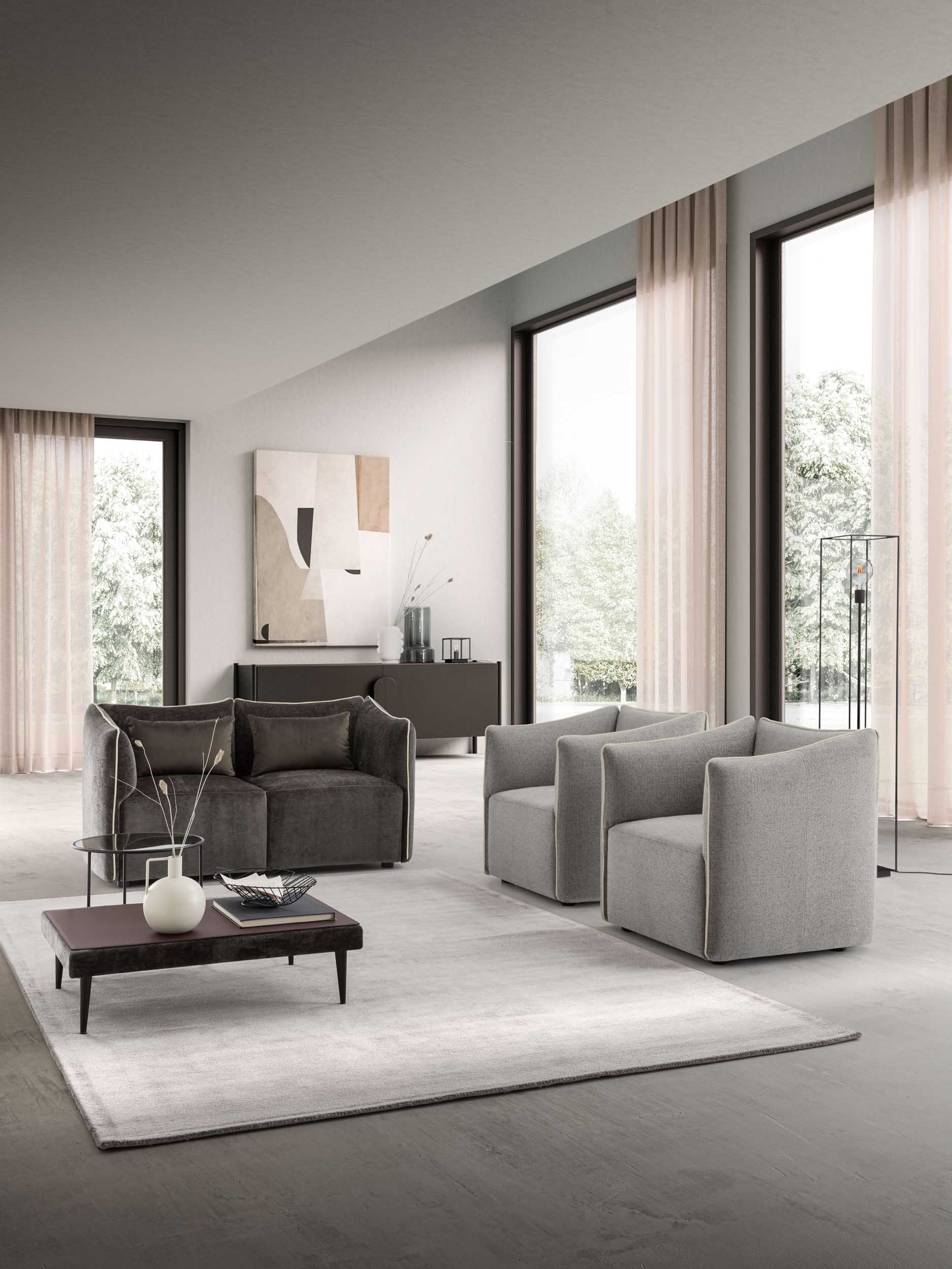 Room furnished with a dark gray loveseat with padded cushions and armchairs