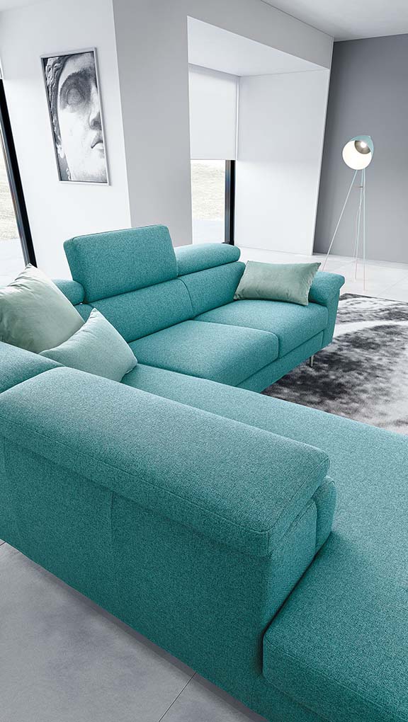 Detail of the turquoise fabric of a sofa with adjustable headrests with contrasting green cushions