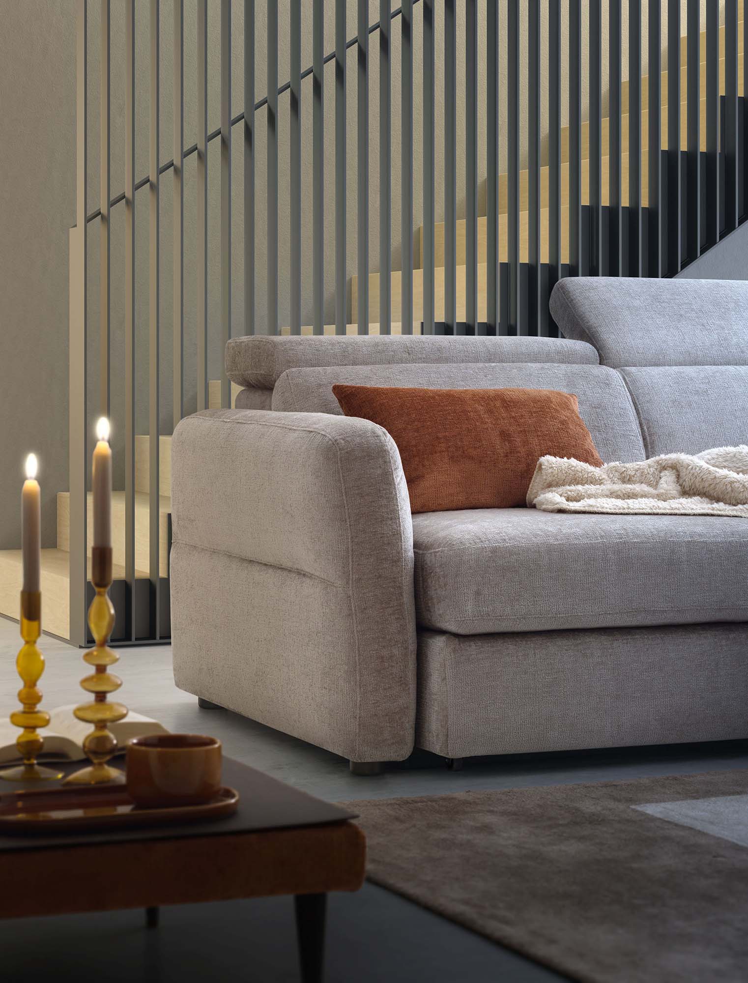 Detail of the quilted armrest of a gray sofa with adjustable headrests