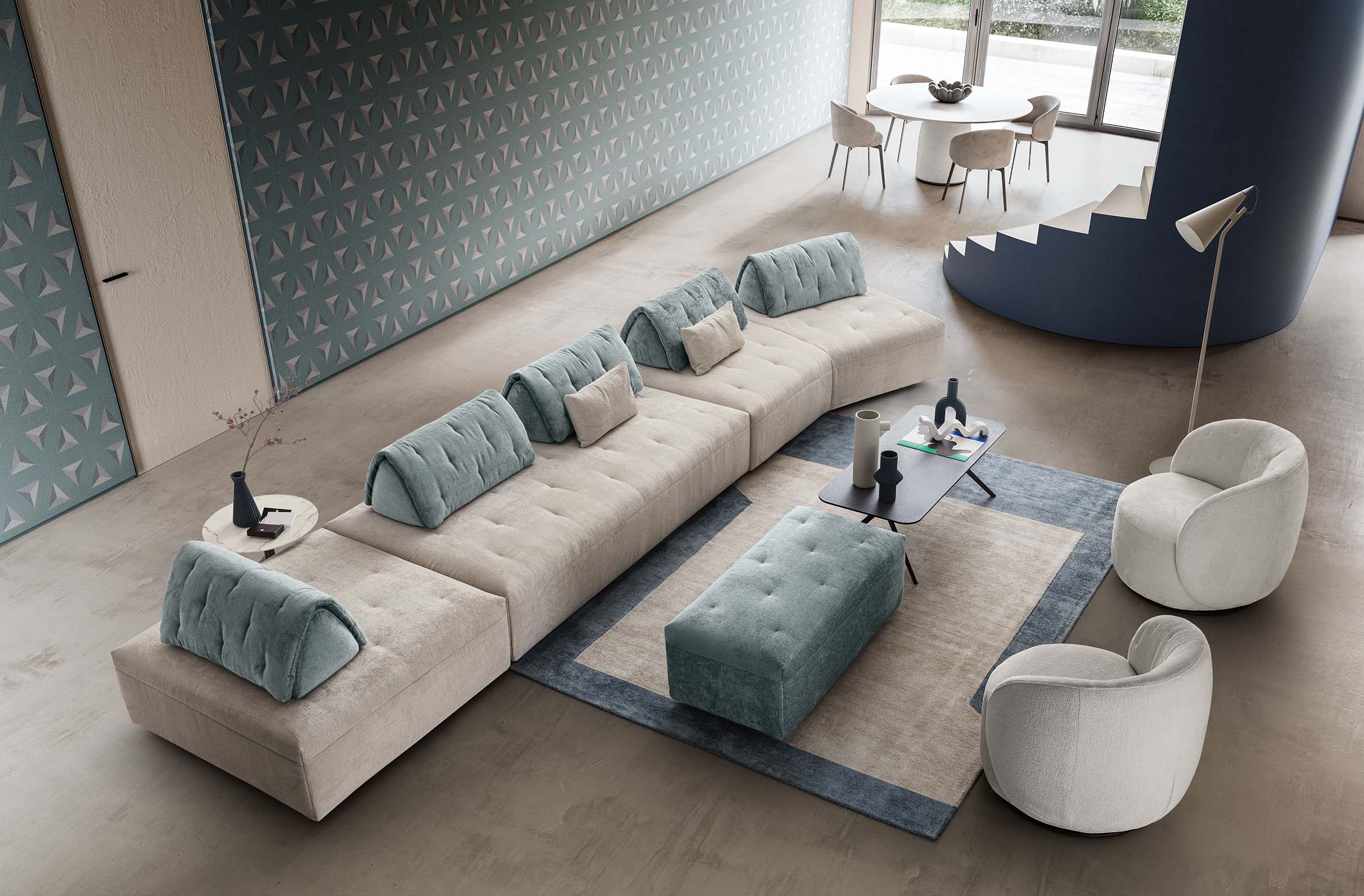 Modular sofa in a linear composition with an asymmetrical side seat. Pouf and armchairs for completion