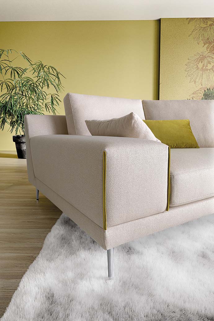 Detail of the khaki-colored stitching on the armrest of a white sofa