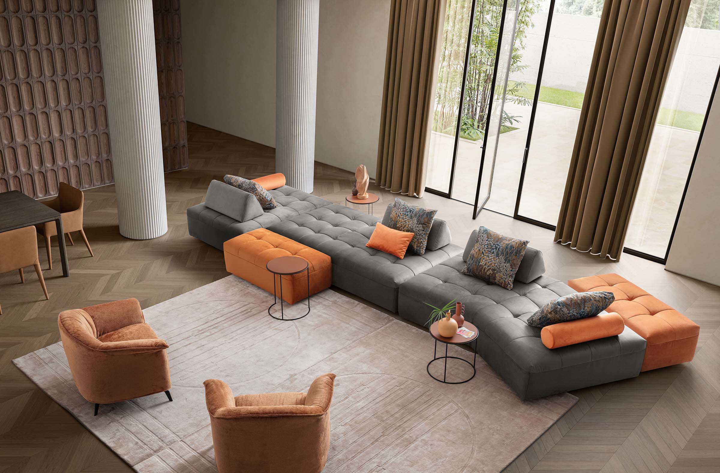 Living room: modular sofa composed of grey and orange modules and two armchairs to complete the composition.