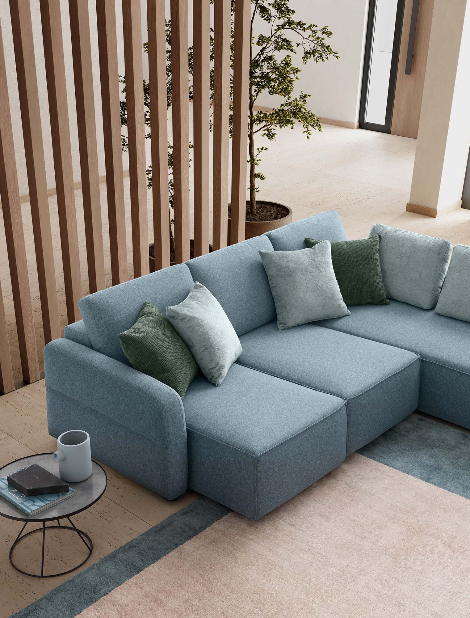Sofa with wide pull-out seats, three-seater. Light blue color with green and light blue cushions and quilted armrest