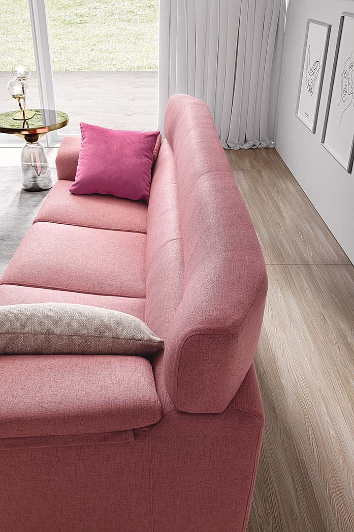 Powder pink sofa with wide seat and high backrest adorned with two fuchsia and cream cushions