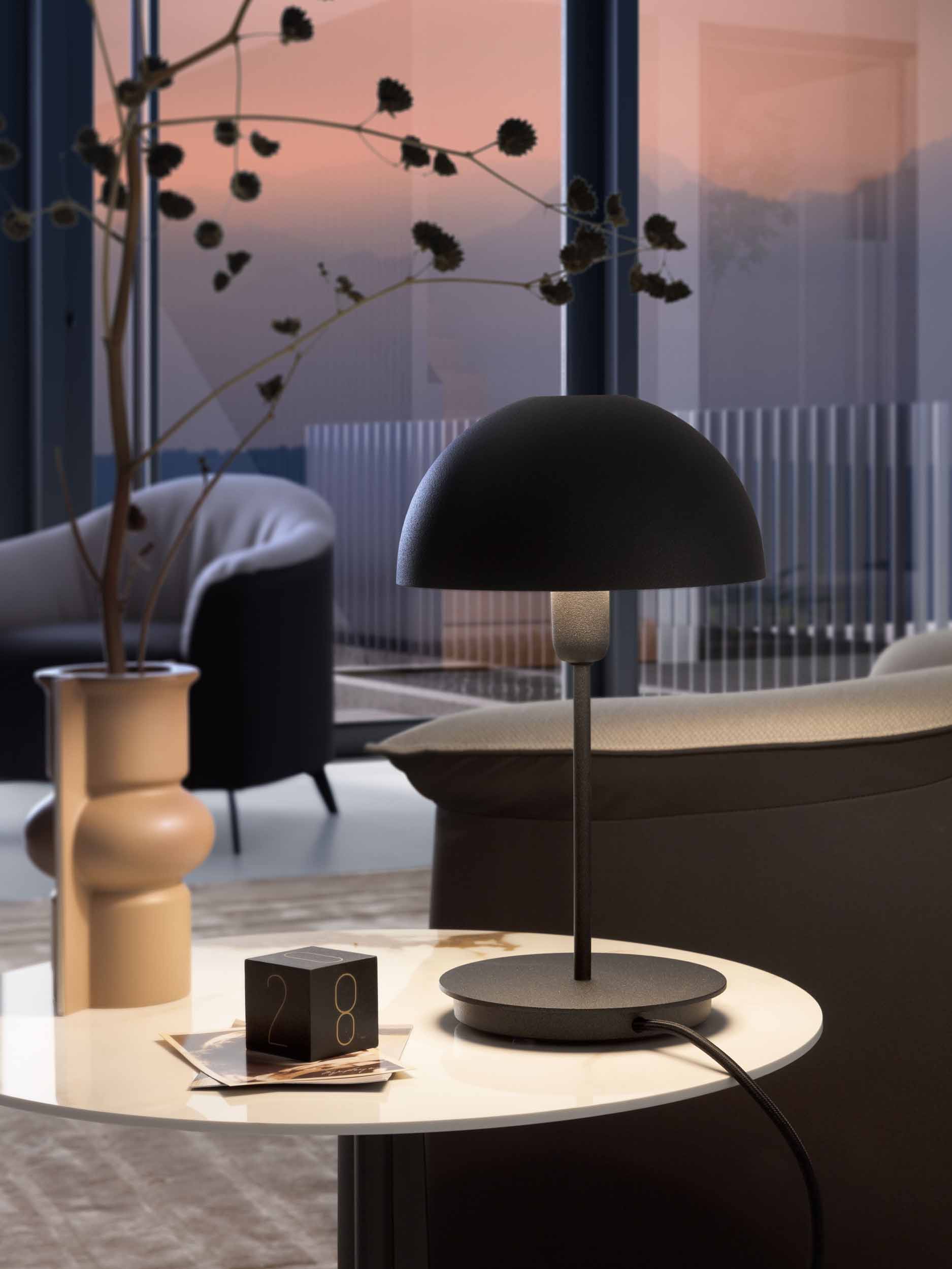 Lamp with hemispherical lampshade lit above a coffee table