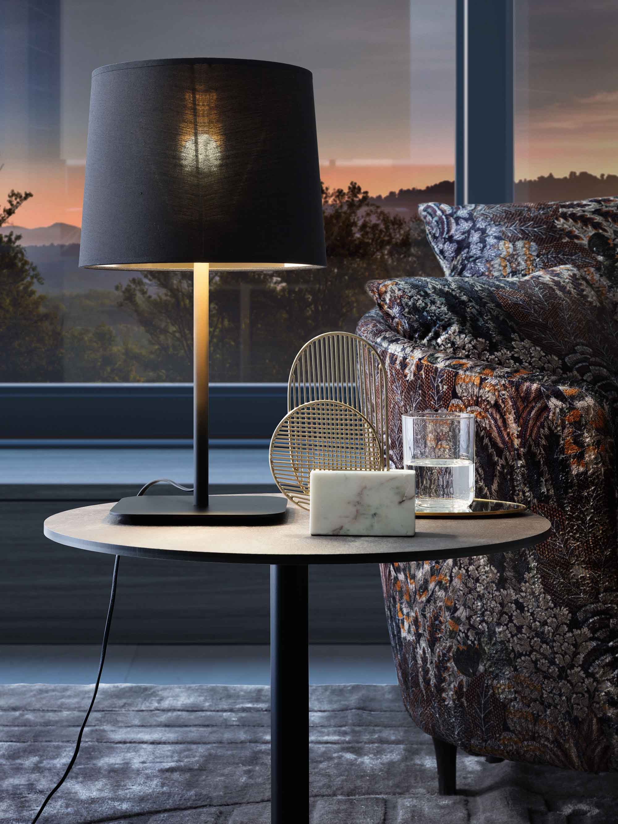 Table lamp with black lampshade and diffused light emission in the living room.