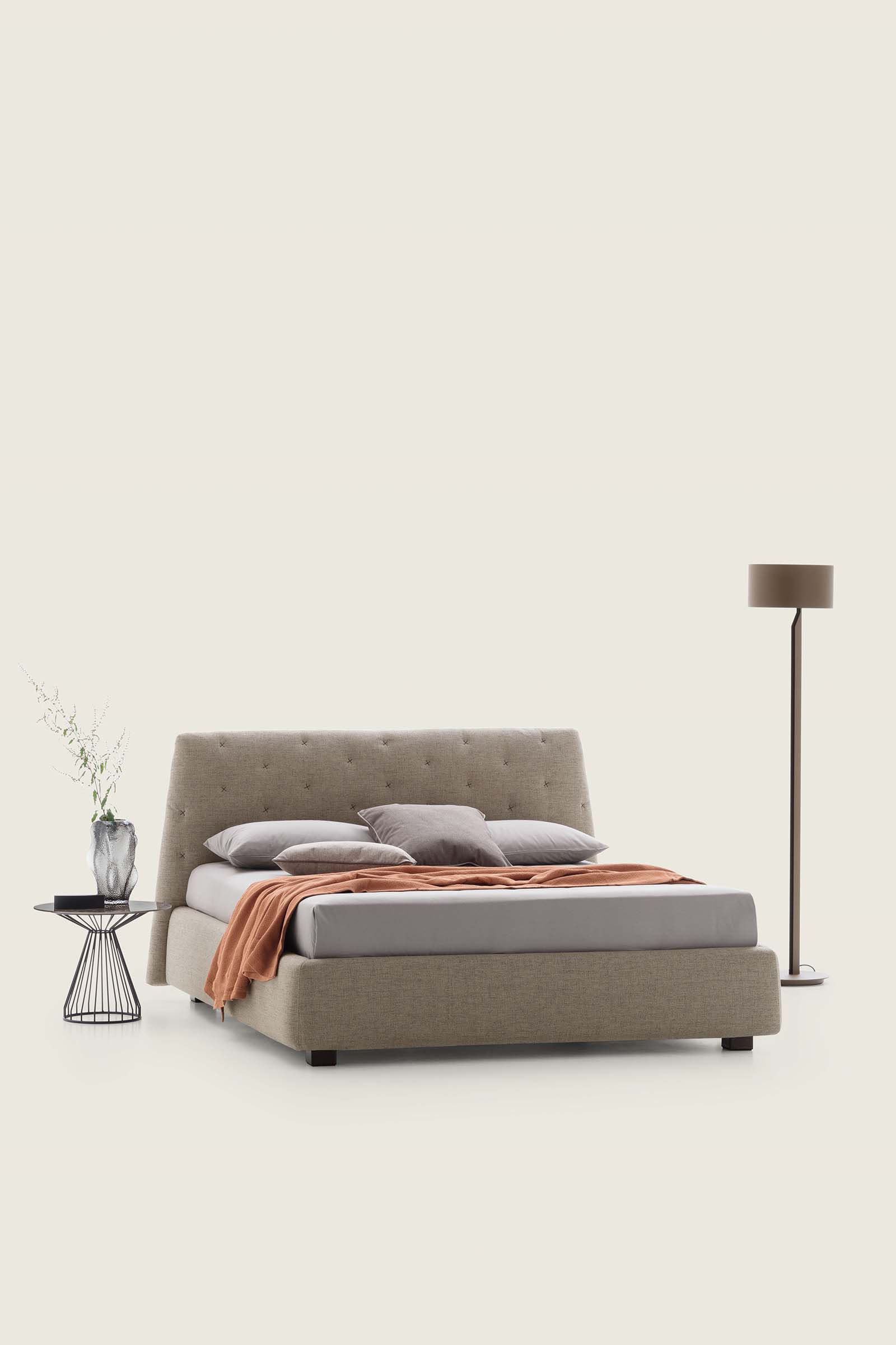 Cream-colored bed with low feet and wide bed frame. Quilted headboard