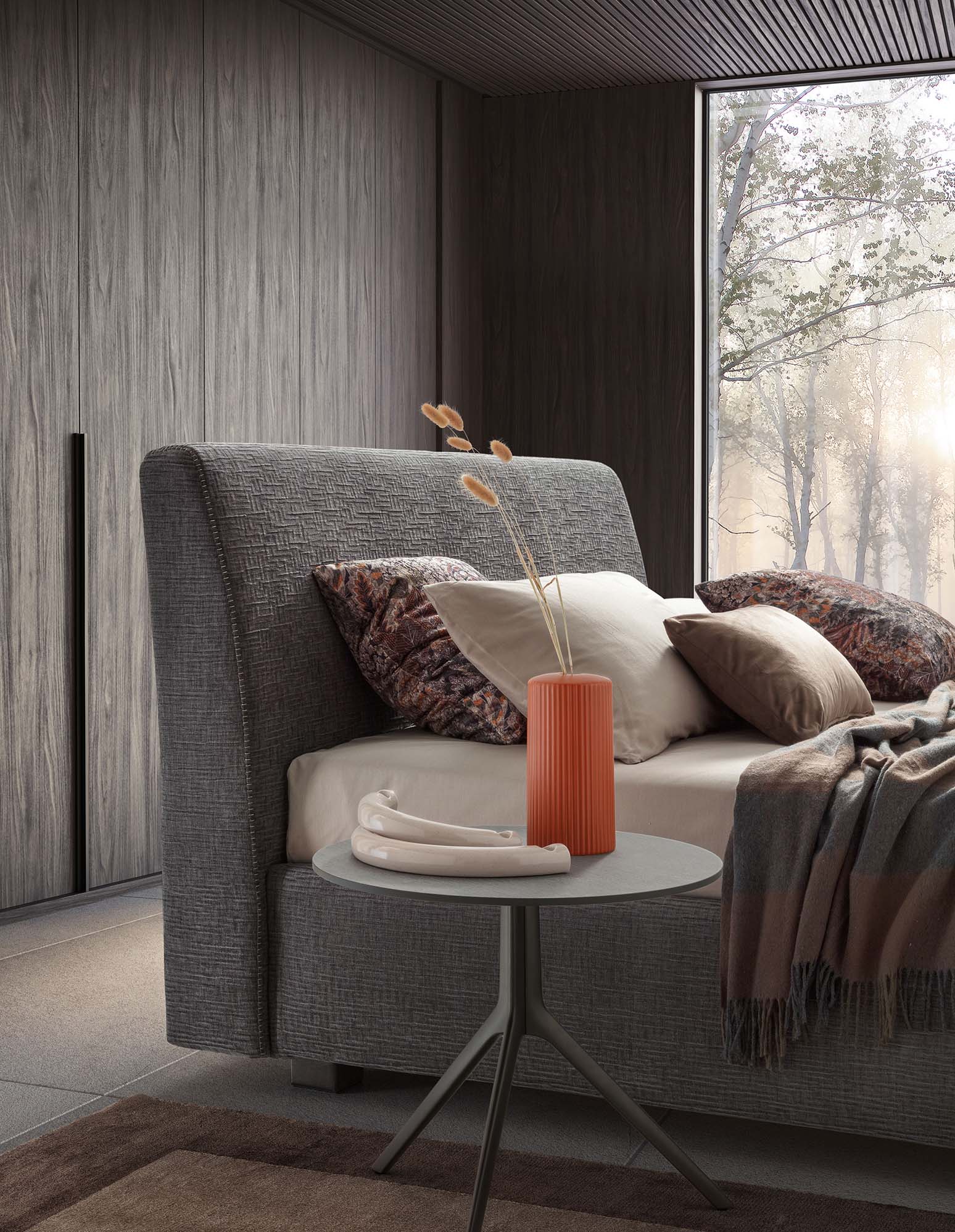 Gray upholstered bed placed in a modern and minimal room with a matching small table