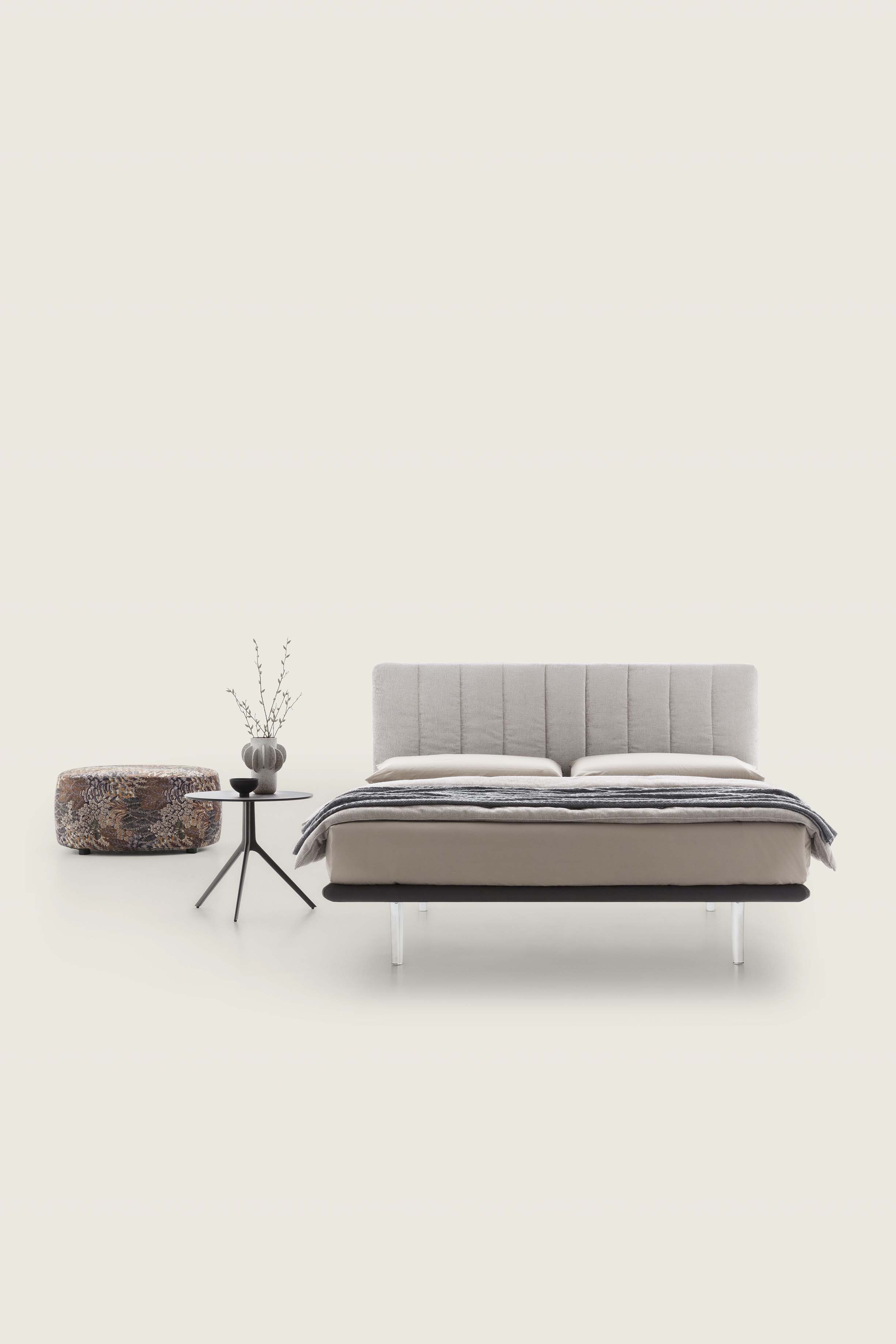 Cream-colored bed with high transparent feet and very thin midnight blue bed frame