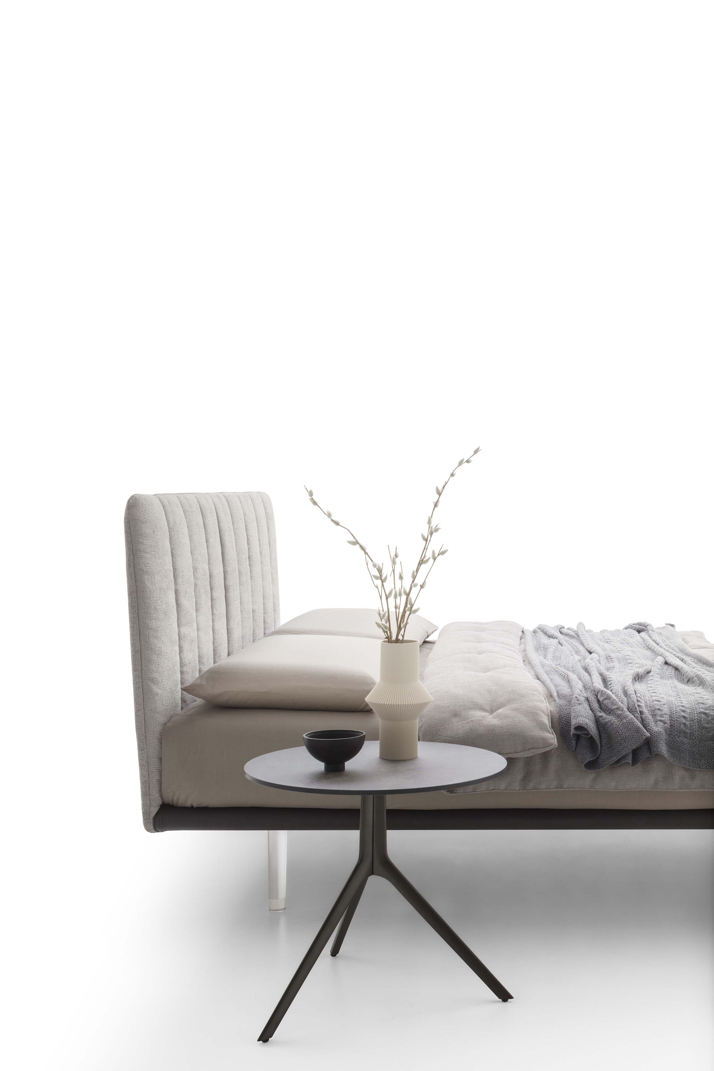 Side view of a fabric upholstered bed with vertical band headboard and matching small table