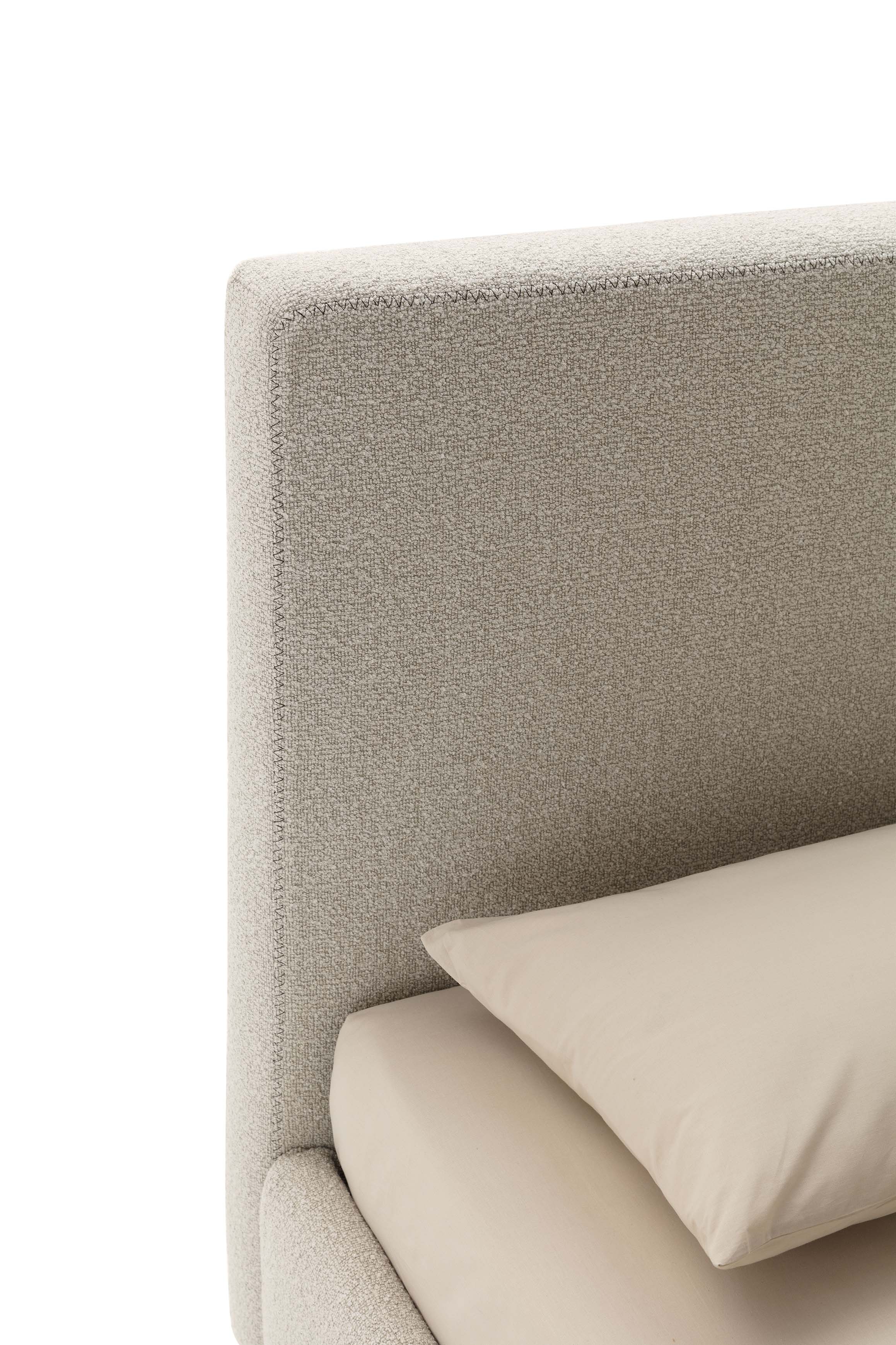 Detail of the simple and square headboard with cream-colored linens