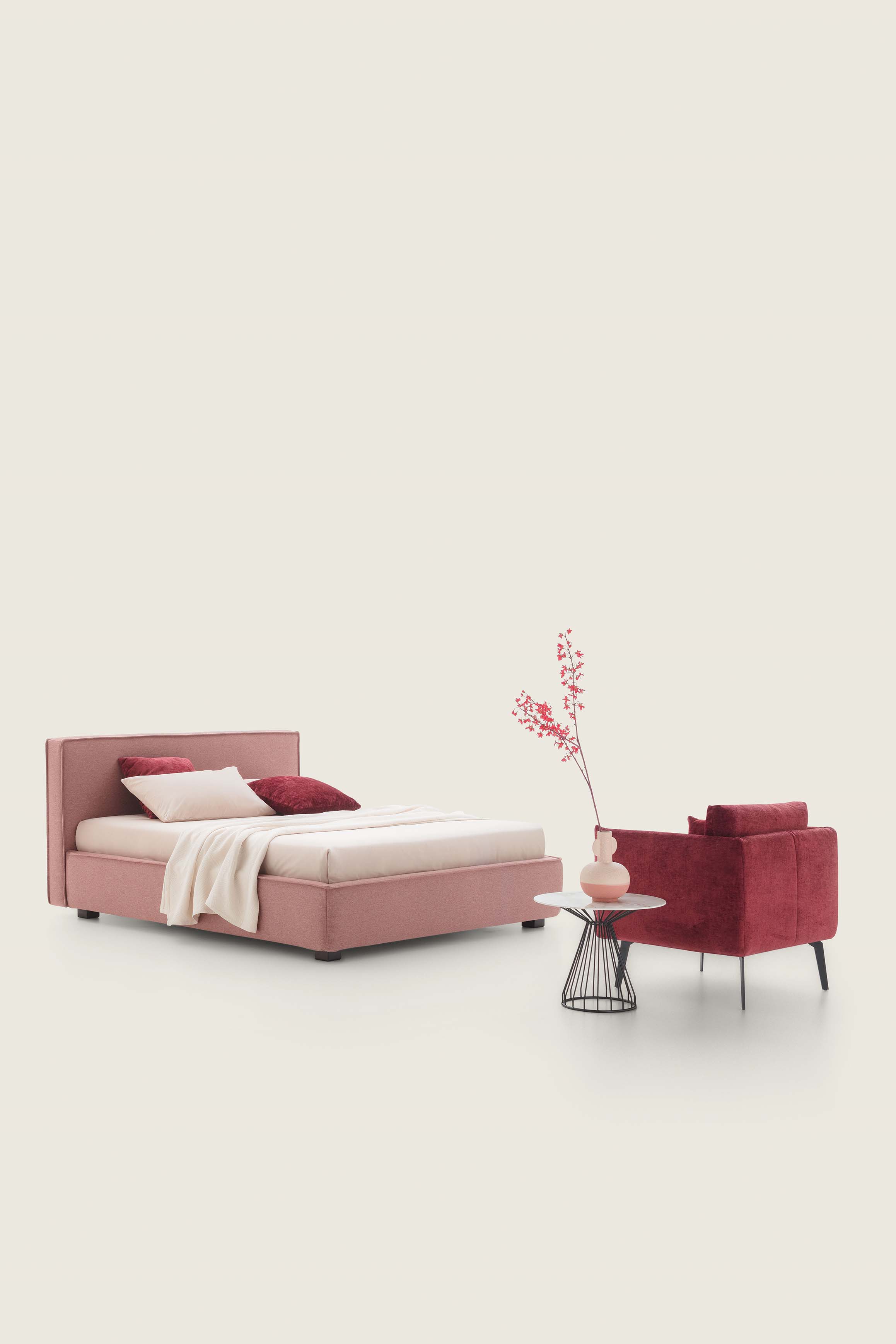 Low powder pink double bed combined with a burgundy armchair