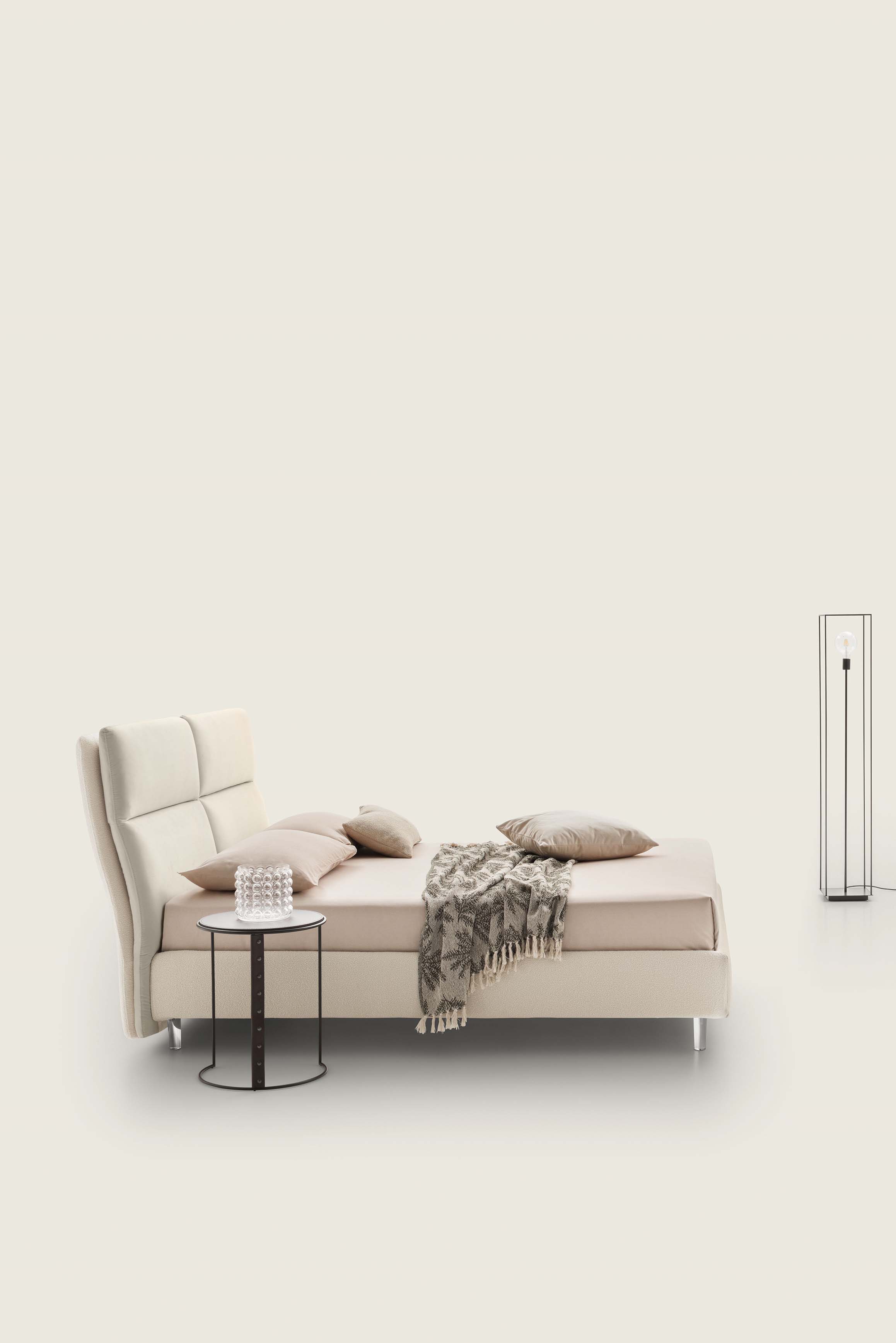 Cream-colored double bed with high fabric-covered headboard combined with a modern coffee table