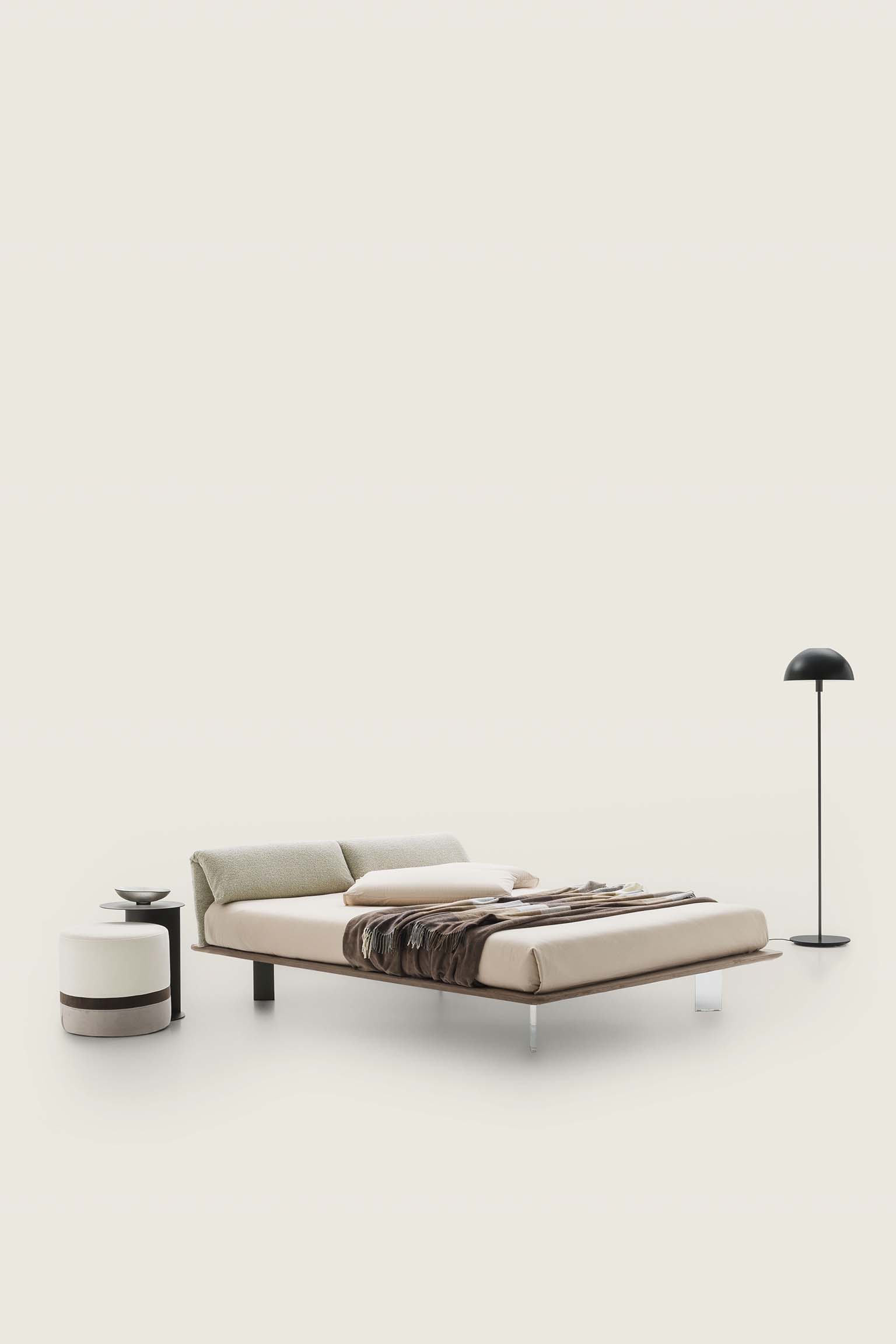 Modern bed with brown bed frame and cream-colored headboard with folding cushions