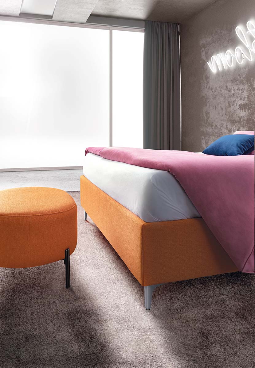 Detail of the footboard and a matching pouf, color Denver 307: thick textured orange fabric