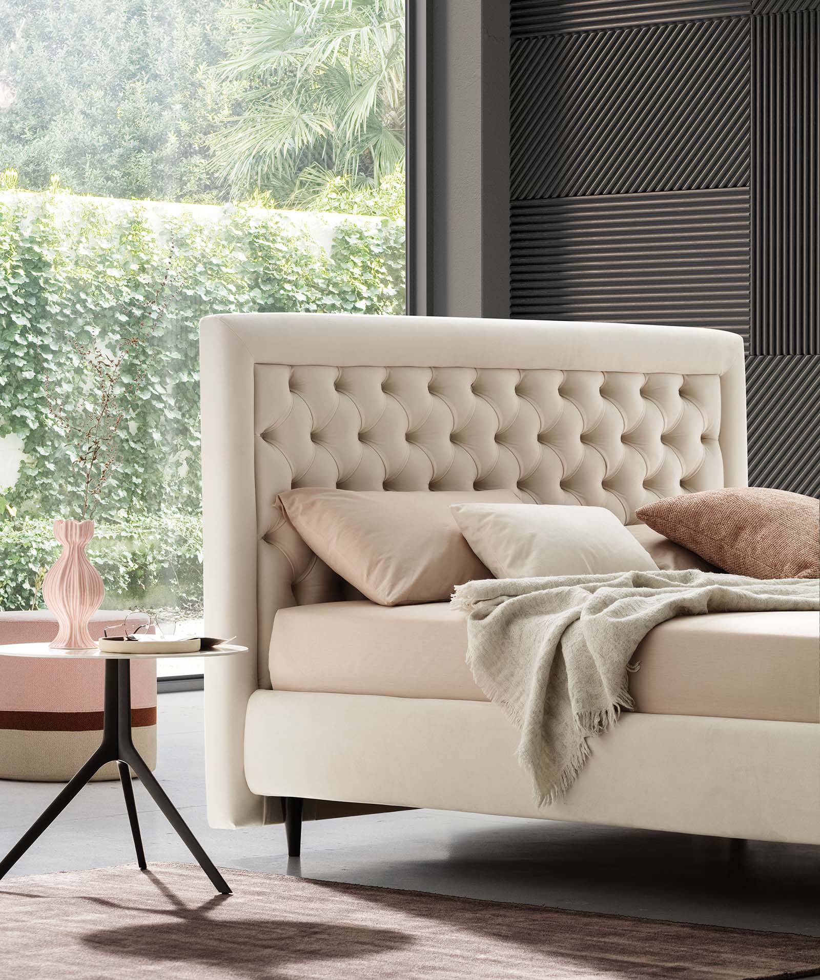 Chesterfield style double bed with cream-colored capitonné headboard in a modern setting