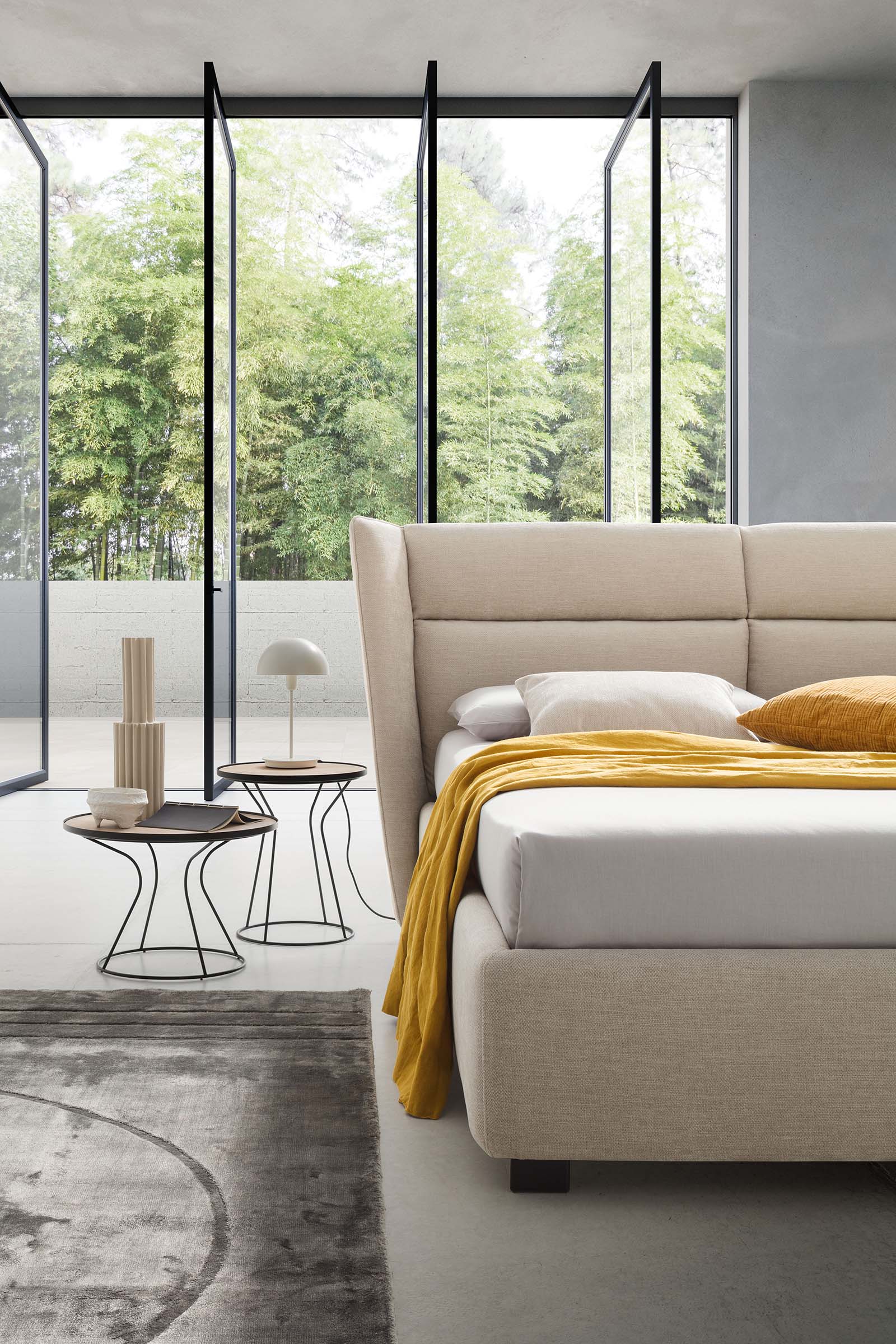 Modern room furnished with a low bed with high headboard and tall bed frame