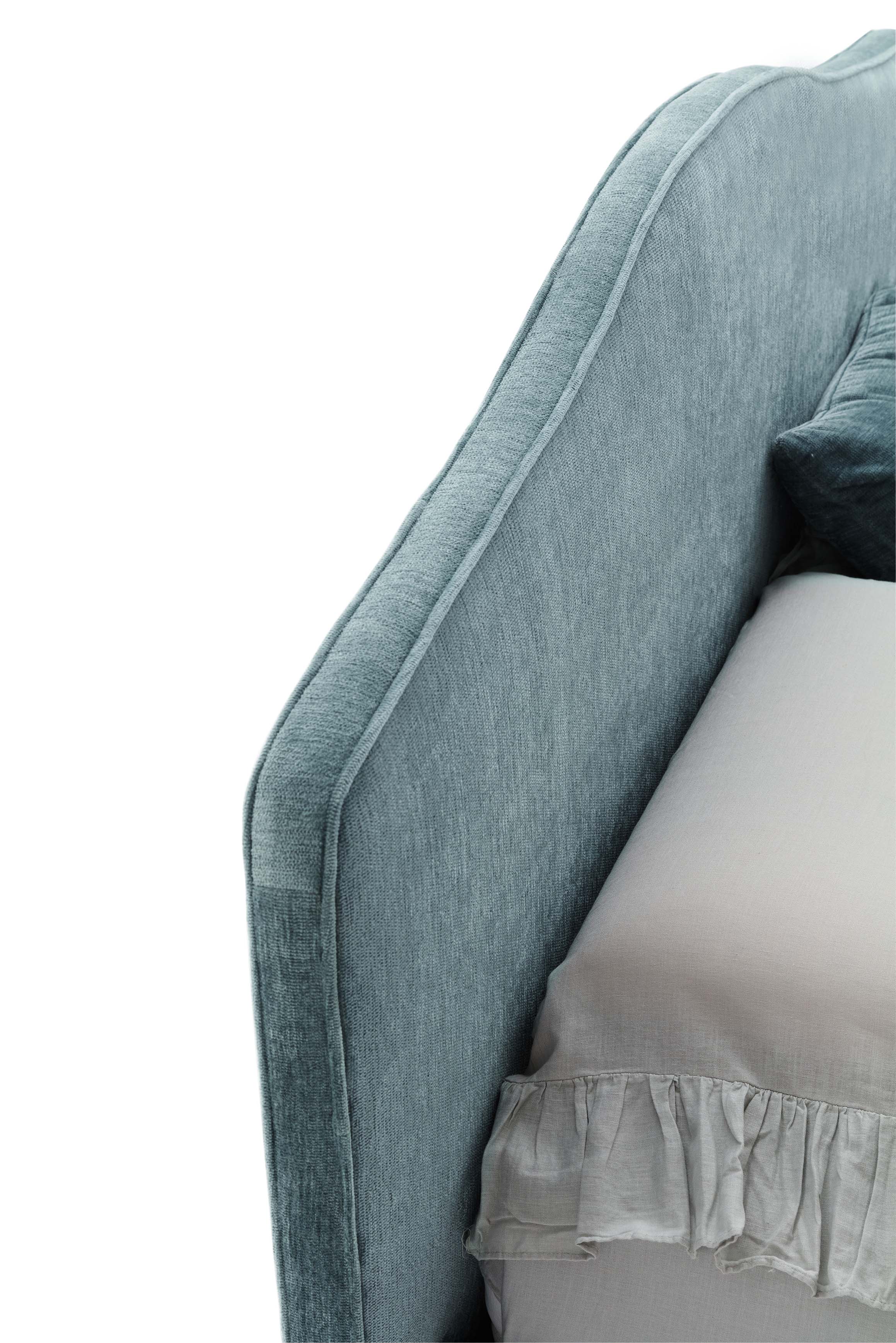 Detail of the light blue fabric headboard with piping