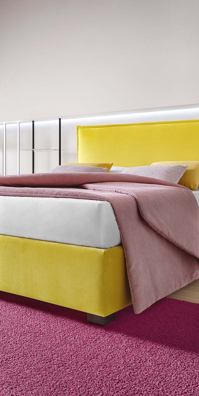 Bed with very low feet and smooth upholstered headboard in soft fabric