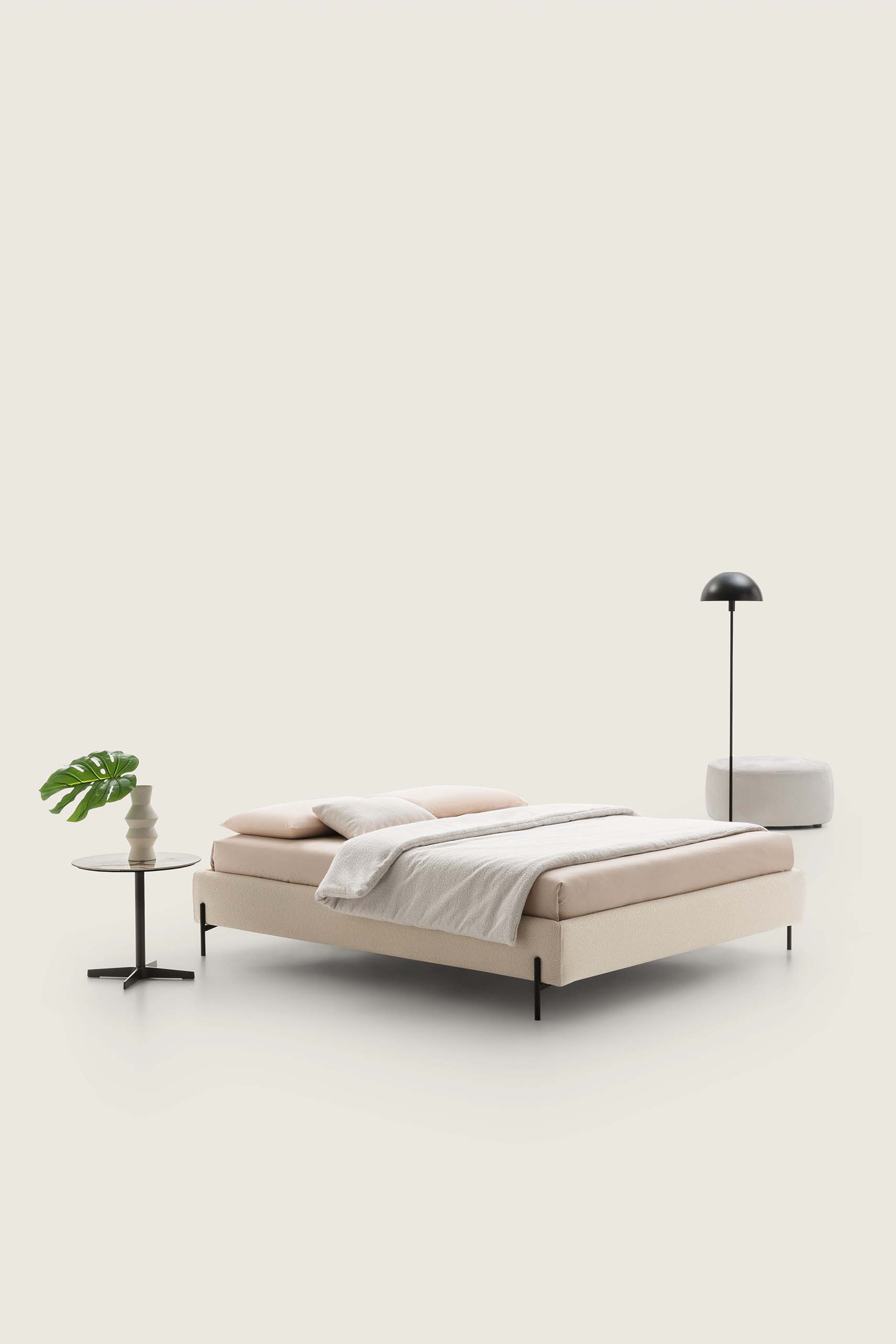 Cream-colored double bed without headboard combined with poufs and night tables