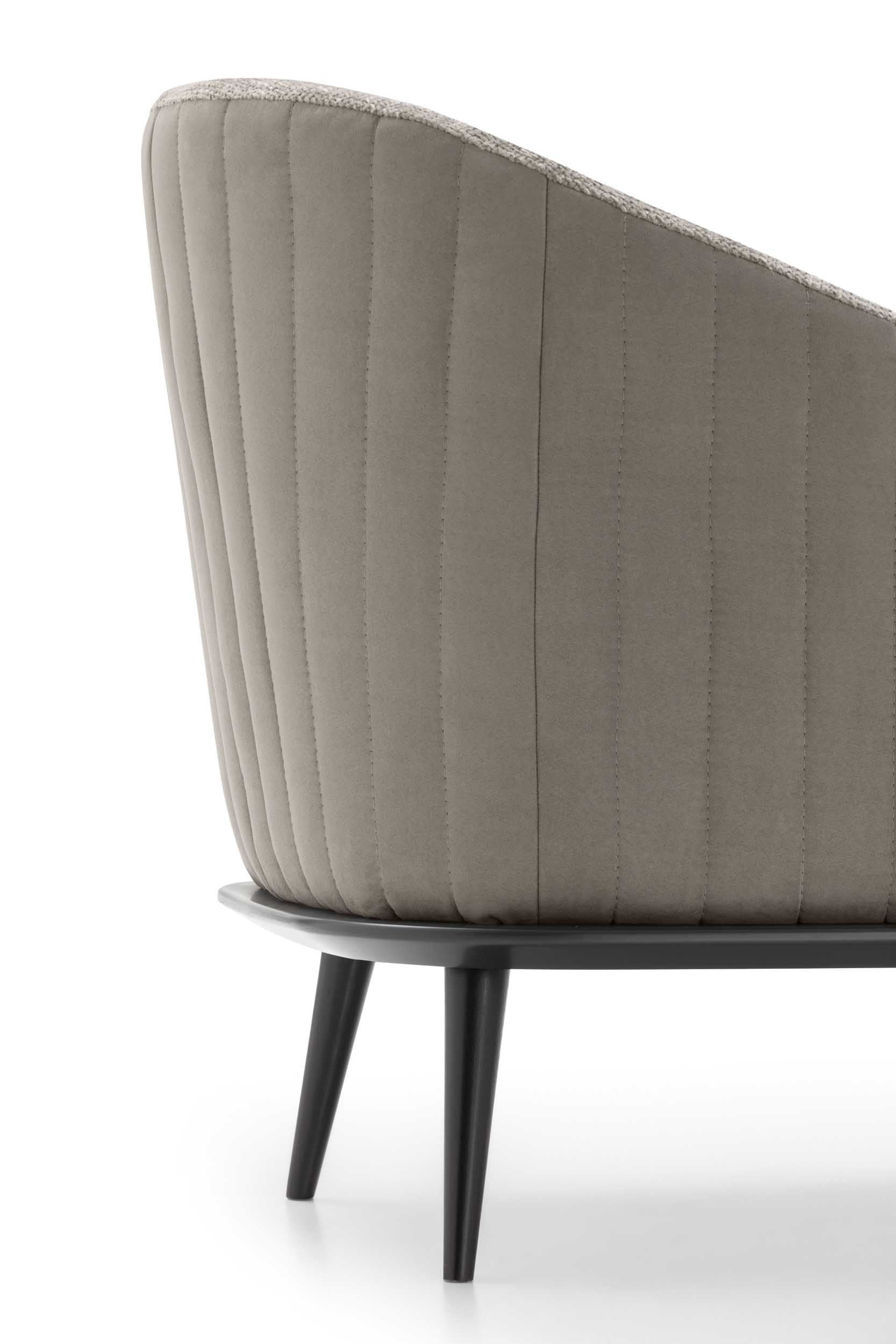 Striped vertical quilting on the back of an armchair with modern black legs.