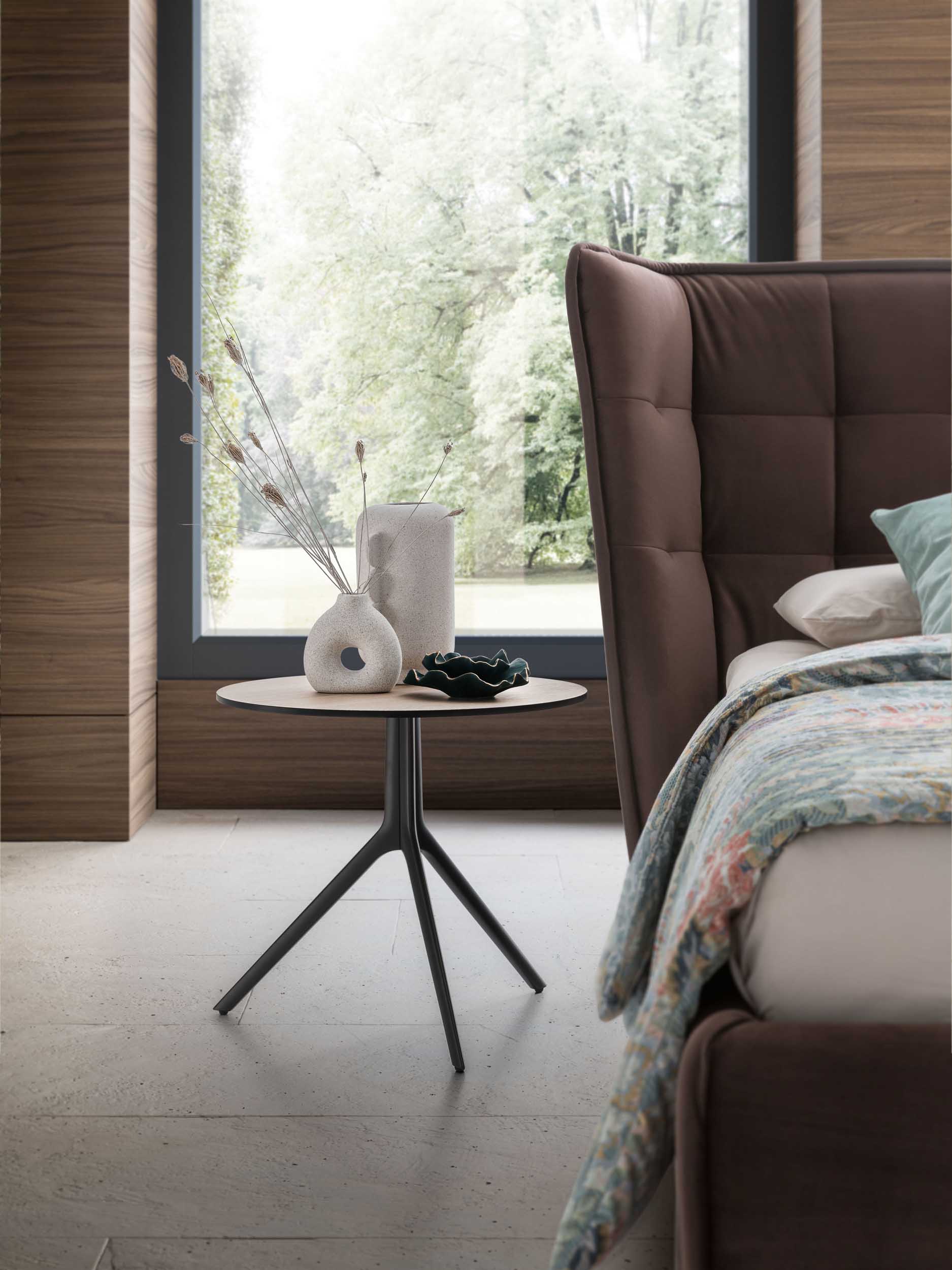 Designer side table placed next to a bed as a nightstand.